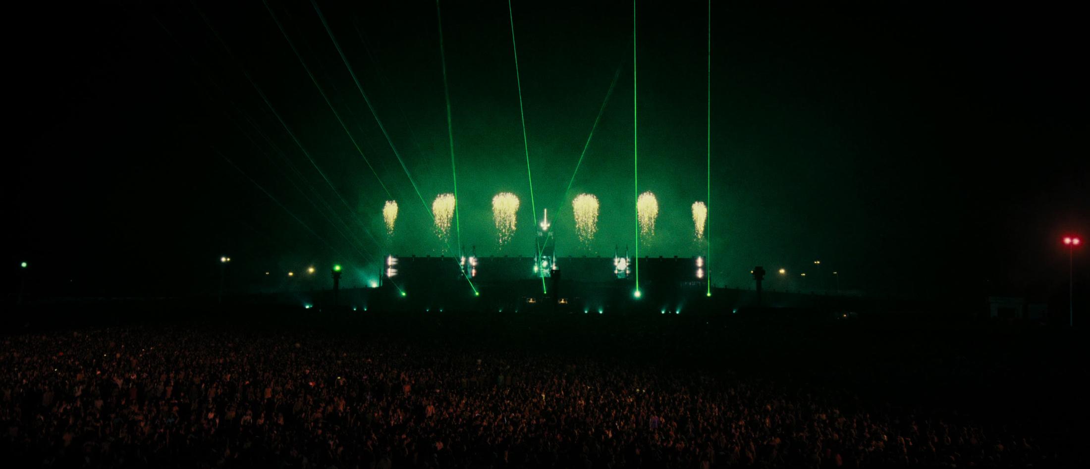 A festival at night: the stage with green lasers over the crowd